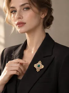 Elegante Vintage Gold Brosche mit grünem Kristall auf einem schwarzen Damen Blazer.