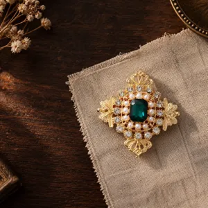 Detailansicht einer Vintage-Brosche im Hofstil mit smaragdgrünem Kristall und Perlen