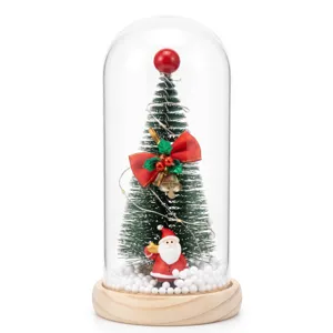 Exquisite miniature glowing Christmas tree in a glass dome with festive Santa Claus ornament