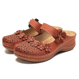Close-up of vintage brown floral clogs with laser-cut patterns and metal studs