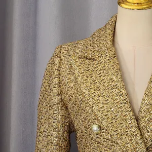 Detailed view of a luxury golden tweed blazer with a pearl button and lapel.