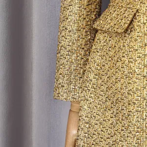 Detailed view of luxury gold metallic tweed fabric on a tailored women's coat sleeve
