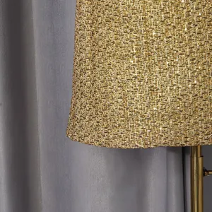 Macro detail of a shimmering gold tweed coat hem showing rich metallic woven texture