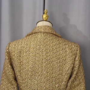 Close-up detail of the gold sequined tweed texture on an elegant mid-length women's jacket