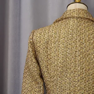 Detailed macro shot of shimmering golden tweed fabric on high-end women jacket