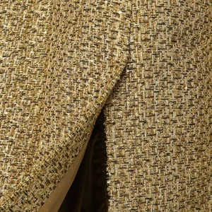 Detail macro view of golden sequin tweed fabric texture for luxury windbreaker coat