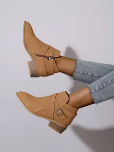 Side profile of tan pointed toe ankle boots with block heel and buckle detail.