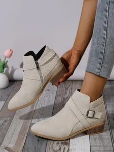 Detail view of women's pointed-toe beige suede ankle boots with side zipper and block heel.