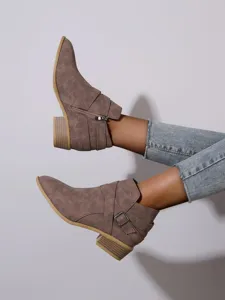 Detail view of taupe pointed-toe ankle boots with side zipper and decorative buckle strap