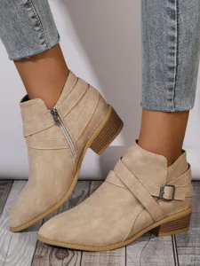 Detail of women's beige suede pointed toe ankle boots with buckle and side zipper.