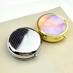 Primo piano dettagliato di portapillole in metallo da 6 cm in oro e argento con marmo