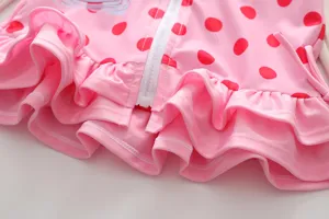 Detail of girls pink polka dot swimsuit featuring a white front zipper and ruffles