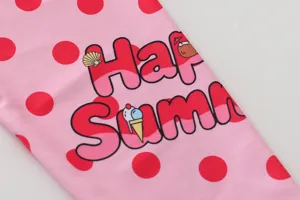 Detail of pink polka dot fabric with Happy Summer print on girls' long-sleeved swimsuit