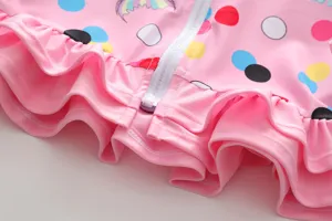 Close-up detail of pink polka dot girl's swimwear featuring white zipper and ruffles