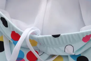 Detail view of girls' polka dot swimsuit waistband with white mesh lining and drawstring.
