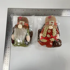 A pair of Harvest Festival turkey gnomes plush dolls measured for size with scale