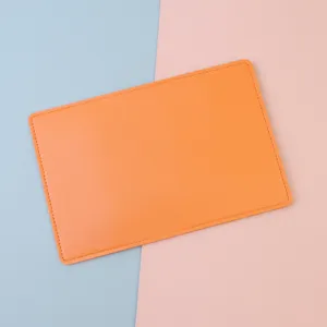 Close-up of vibrant orange leather passport cover with clean stitching on pastel background