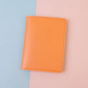 Close-up of bright orange minimalist leather passport cover with visible stitching