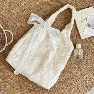 Détail de la broderie de rose et du nœud en dentelle sur un sac cabas beige
