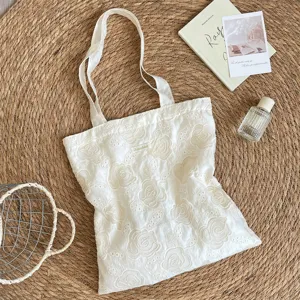 Gros plan sur un sac fourre-tout crème orné d'élégantes broderies de roses françaises.