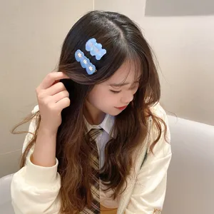 Close-up detail of cute blue cartoon hair clips with sweet bear and rabbit designs for girls.