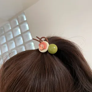 Close-up detail shot of a cute quirky face pendant hair tie and green bead ponytail holder.