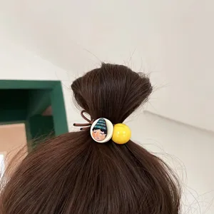 Close-up detail of the cute cartoon face and yellow ball hair tie worn on brown hair bun.