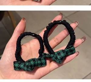 Détail de l'élastique à cheveux pied-de-poule avec nœud vert et noir et grande élasticité.