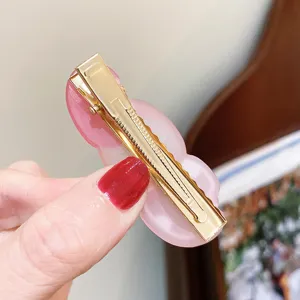 Detailed close-up view of the cute pink resin hair clip featuring gold metal duckbill backing.