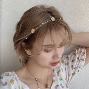 Detail view of the stylish metal headband featuring cute orange charms and sparkling rhinestones.