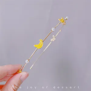 Close-up of a delicate metal headband featuring cute yellow banana and pearl charms.