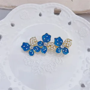 Elegant blue floral hair clip detail displaying enamel craftsmanship and rhinestones.