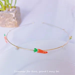 Minimalist metal headband featuring enamel carrots and pearls, detailed close-up shot.