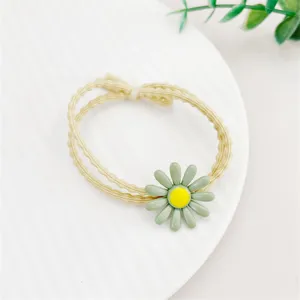 Détail de chouchou marguerite vert charmant, montrant une fleur délicate sur bande élastique.
