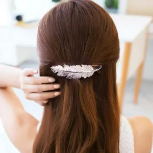 Close-up detail shot of a silver feather hair clip worn gracefully on brown hair.