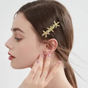 Gold starfish hair clip for women, elegant metallic side pin, stylish hairpin hair accessory.