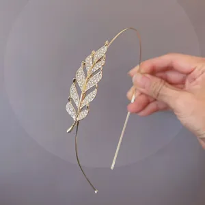 Close-up of the exquisite rhinestone leaf detail on a sleek gold-tone thin hair hoop.