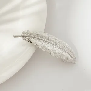 Close-up detail shot of a silver feather hair clip, showing exquisite leaf texture and shiny metal.