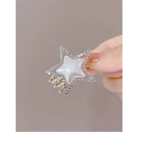 Close-up of a sparkling star hair claw clip featuring rhinestones and a pearl center.