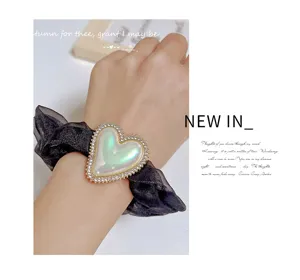 Élégant chouchou en organza noir doté d'un joli pendentif cœur irisé en strass pour les dames.