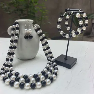 Dettaglio del set di gioielli di perle in bianco e nero, collana multi-filo e orecchini a cerchio.