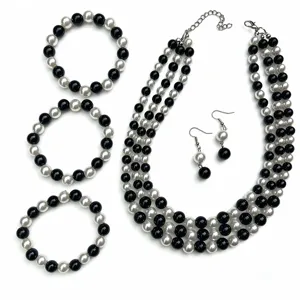 Elegante set di gioielli in perle artificiali bianche e nere con collane e orecchini abbinati.