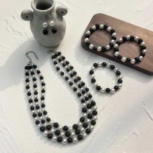 Elegante set di gioielli in perle sintetiche con collana multistrato, bracciali e orecchini.