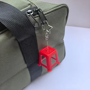 Red miniature stool keychain detail showing the plastic stool, metal star clasp, and chain.