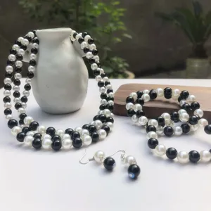 Vista dettagliata di un set di gioielli in perle artificiali bianche e nere con collana a più fili.