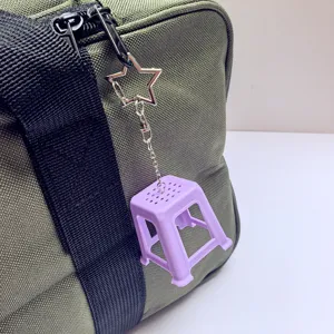 Mini plastic stool keychain detailed shot, cute creative nostalgic bag pendant accessory.