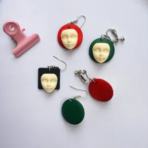 Handgemaakte eigenzinnige houten oorbellen met gezicht, geometrische kleurrijke sieraden.