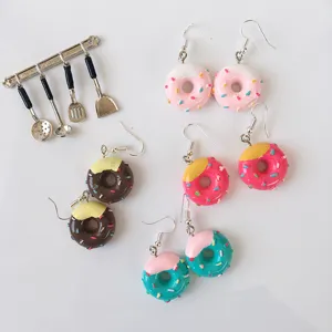 Nahaufnahme handgemachter Miniatur Donut Ohrringe mit bunter Glasur und niedlichem Streusel-Design.