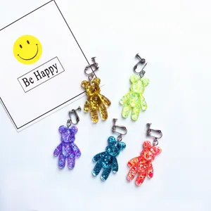 Close up of colorful glitter resin teddy bear clip on earrings, detailed texture and metal.