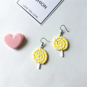 Detailed shot of cute yellow and white polymer clay lollipop earrings, playful style.